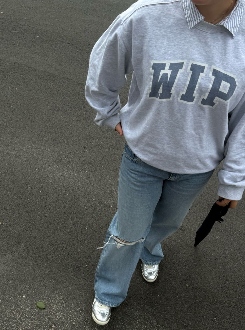 Effortlessly cool without trying too hard — an oversized grey WIP sweatshirt layered over a classic striped blouse, relaxed light-wash ripped jeans, and metallic silver sneakers. The mix of vintage Americana, casual streetwear, and clean minimal details makes this the kind of everyday outfit that somehow looks insanely put together. ☁️🩶

Simple, comfortable, a little nostalgic — and very off-duty cool girl.